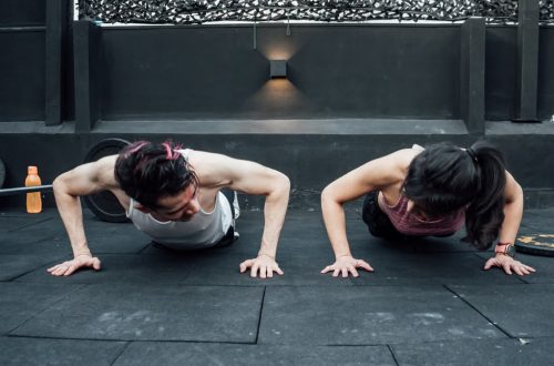 Two adults doing push-ups in an indoor gym setting in Mexico City, promoting a fit and healthy lifestyle.