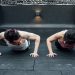 Two adults doing push-ups in an indoor gym setting in Mexico City, promoting a fit and healthy lifestyle.